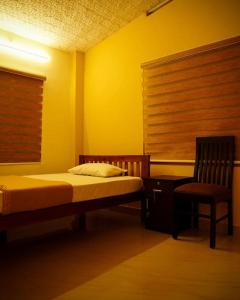 a bedroom with a bed and a chair and a window at New Heaven Group accommodation in Thekkady