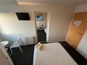 Cette chambre comprend un lit, une table et une télévision. dans l'établissement L'Escale d'Alès HOTEL, à Alès