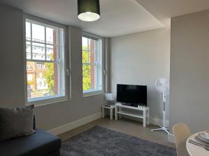 een woonkamer met een bank en een flatscreen-tv bij Bright, spacious 1 bedroom flat in Brentwood