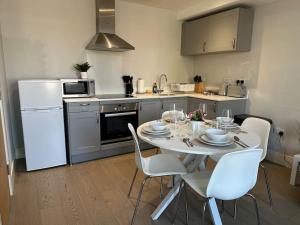 een keuken met een tafel met witte stoelen en een witte koelkast bij Bright, spacious 1 bedroom flat in Brentwood