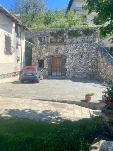 een auto geparkeerd voor een stenen gebouw met een deur bij Il Casale del Generale in Agerola