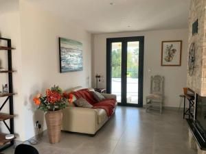 Una sala de estar con un sofá y un jarrón con flores. en Rez de maison neuve Piscine WiFi Poolhouse en Pierre, en Penta-di-Casinca
