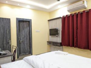 Camera con letto, tende rosse e TV. di GRG TRS Inn Ranchi a Rānchī