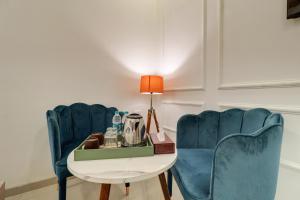 Zimmer mit 2 blauen Stühlen und einem Tisch in der Unterkunft Hotel Aura Dombivali in Dive
