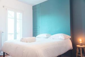 a bedroom with a white bed with a blue wall at L'Etape - La Maison des amis in Tours