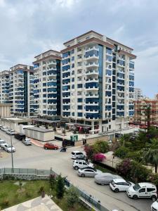 SA Apartments! 1bd Flat 300m to the Beach في ألانيا: مبنى كبير به سيارات تقف في موقف للسيارات