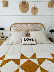 un letto con un cuscino con la parola amore sopra di Cabane le Flamant avec jardin, piscine chauffée et parking a Saintes-Maries-de-la-Mer