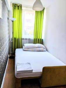 łóżko w pokoju z zielonymi zasłonami i oknem w obiekcie Ursus Rooms-Self Check-in w Warszawie