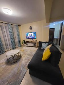 a living room with a black couch and a tv at Javic Home in Nakuru