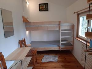 a room with a bunk bed and a table and a desk at Domek Drewniany in Nowa Wola