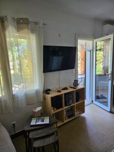 een woonkamer met een flatscreen-tv aan de muur bij Les Lambrusques T2 avec jardin à 300 m de la plage in Cavalaire-sur-Mer