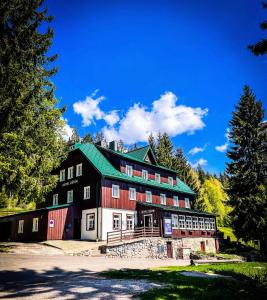 un grande fienile rosso e bianco con tetto verde di Hotel Děvín a Pec pod Sněžkou