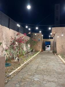 una pasarela con flores y luces en un edificio en شاليهات حائط طيني en Riad