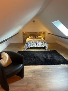 a bedroom with a bed and a chair in a attic at La p tite maison in Gien