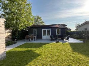 un patio trasero con una mesa y sillas y una casa en Knus familiehuisje nabij Bergen en Schoorl, en Warmenhuizen