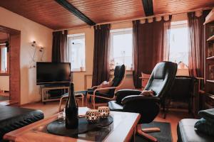 sala de estar con sillas negras y TV en Hexenhütte, en Sankt Andreasberg