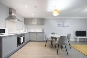a kitchen with white cabinets and a table and chairs at Cosy, Bright and Spacious Flat in Brentwood