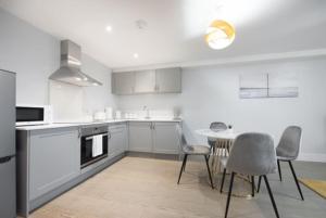 a kitchen with white cabinets and a table and chairs at Cosy, Bright and Spacious Flat in Brentwood