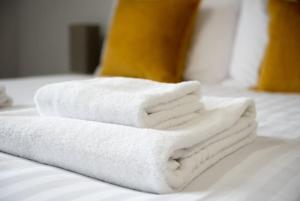 three white towels are stacked on a bed at Cosy, Bright and Spacious Flat in Brentwood