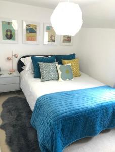 una camera da letto con un letto con una coperta blu e cuscini di Newly Renovated 5 Star Cosy-Up Romantic Cottage NEAR LONGLEAT a Warminster