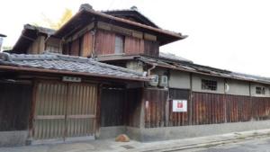 44-49 Bishamoncho - Hotel / Vacation STAY 7917 في كيوتو: مبنى خشبي قديم وبه كلب يجلس أمامه