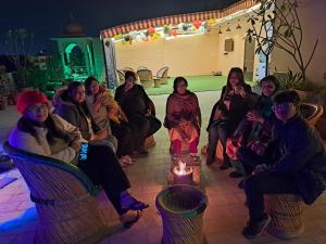 um grupo de pessoas sentadas em cadeiras com uma vela em Swaraj Palace em Jaipur