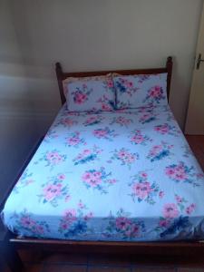 a bed with a blue comforter with pink flowers at Campo dos Sonhos in Serra Negra