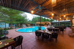 un restaurant en plein air avec des tables et une piscine dans l'établissement Chay Lap Farmstay Phong Nha, à Ðá Lòn