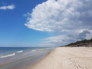 a beach with a cloudy sky and the ocean w obiekcie Libra Mrzeżyno w mieście Mrzeżyno