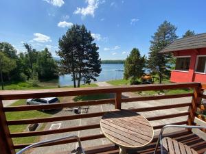 a deck with a table and chairs and a view of a lake at apartmán Maják u Žermanické přehrady in Pitrov