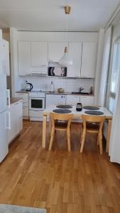 a kitchen with a wooden table and white cabinets at Bright apartment, airport 3km, private parking, sauna in Vantaa