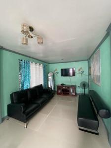 een woonkamer met een zwarte bank en een flatscreen-tv bij AB Yam Staycation Gensan near Venue88 in General Santos