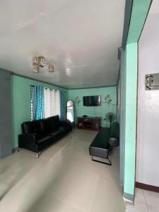 a living room with a black couch and a tv at AB Yam Staycation Gensan (can accommodate up to 15 pax) in General Santos