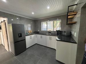 Una cocina con gabinetes blancos y un refrigerador de acero inoxidable. en Villa da Lucia, en St Lucia