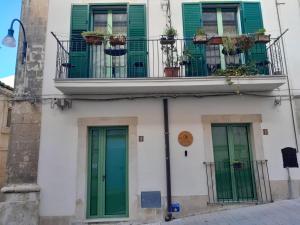 a building with green doors and a balcony at A Calata Rooms in Noto