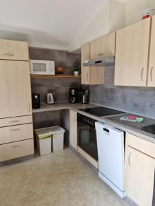 una cocina con electrodomésticos blancos y armarios de madera en Bungalow Loos, en Butjadingen