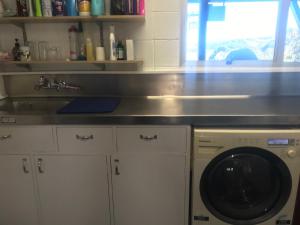 een keuken met een wastafel en een wasmachine bij Brophys Beach Studio in Whitianga