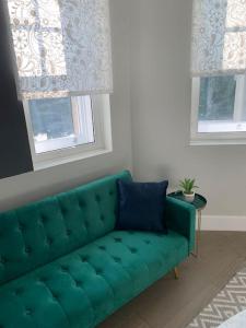 un sofá verde en una sala de estar con 2 ventanas en Two bedroom, modern spacious apartment., en Brentwood