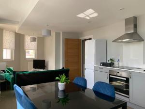 cocina y sala de estar con mesa y sillas azules en Two bedroom, modern spacious apartment., en Brentwood