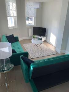 sala de estar con sofá verde y TV en Two bedroom, modern spacious apartment., en Brentwood