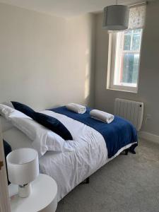 1 dormitorio con 1 cama con manta azul y ventana en Two bedroom, modern spacious apartment., en Brentwood