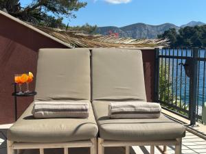 2 Stühle auf einem Balkon mit Blick auf das Wasser in der Unterkunft SeaZen Luxury Seaside Apartment Korcula in Račišće