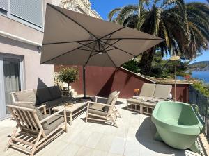 ein Sonnenschirm und Stühle und eine Badewanne auf einer Terrasse in der Unterkunft SeaZen Luxury Seaside Apartment Korcula in Račišće