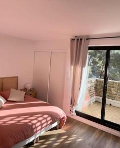 ein Schlafzimmer mit einem Bett und einem großen Fenster in der Unterkunft Duplex T3 avec jardin, bord de mer et parking in Six-Fours-les-Plages