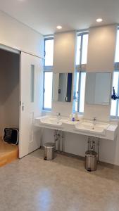 a bathroom with two sinks and two mirrors at ゲストハウスあさひのお宿 in Kurodahara