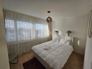 City feel good with forest view في زيورخ: غرفة نوم مع سرير كبير مع ملاءات بيضاء ونوافذ