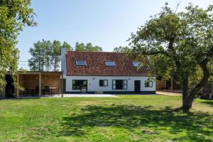 a house with a red roof and a yard at Vakantiehuis Braembeyerhoek in Bruges
