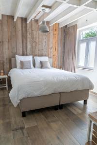 a bedroom with a large bed in a room with wooden walls at Vakantiehuis Braembeyerhoek in Bruges