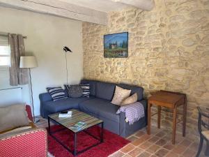 uma sala de estar com um sofá azul e uma parede de pedra em DOMAINE de MAS CARON Gîte 4* au pied du Ventoux en Provence em Caromb