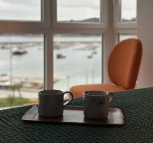 two coffee mugs sitting on a tray on a table at Apartamento Plaza Este in Muxia